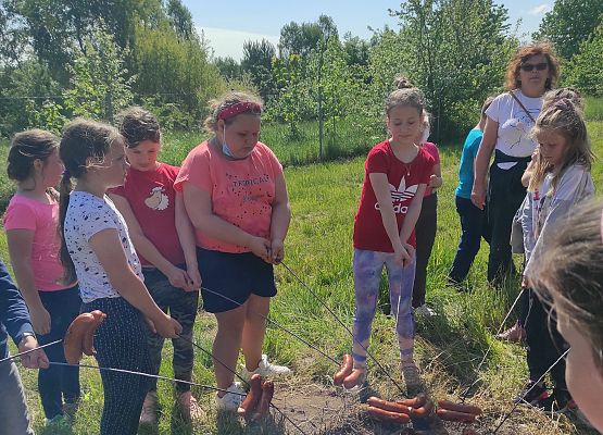 Uczniowie pieką kiełbaski nad ogniskiem