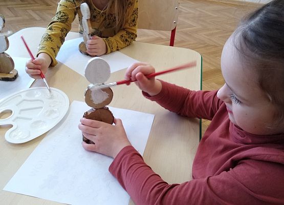 Dzieci wykonują bałwanki z drewna