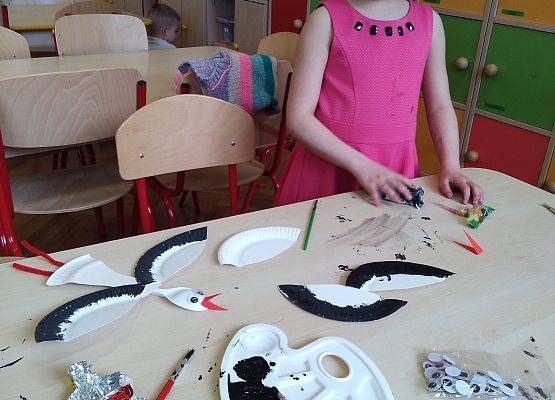 Przedszkolaki robią bociany z talerzyków papierowych