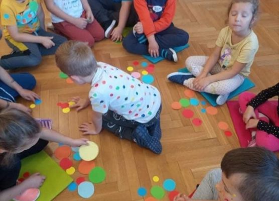 Dzieci bawią się kolorowymi kropkami.