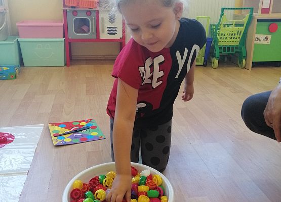 Dzieci bawią się  kolorowymi nakrętksami