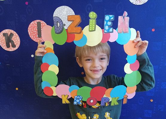 Przedszkolak  trzymający ramkę w kropki.