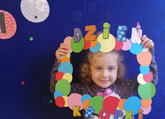 Przedszkolak  trzymający ramkę w kropki.