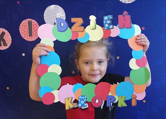 Przedszkolak  trzymający ramkę w kropki.