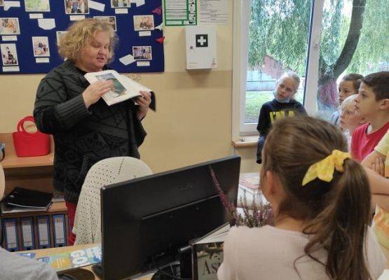 Pani w bibliotece prezentuje ksiązkę