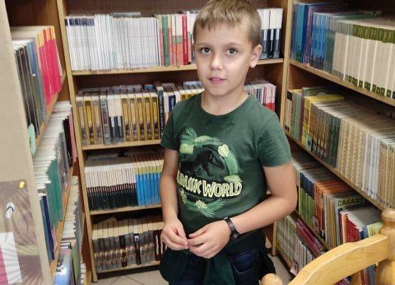 Uczeń stoi przy regale z książkami