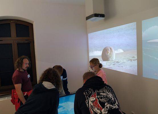 Uczniowie z przewodnikiem oglądają wystawę