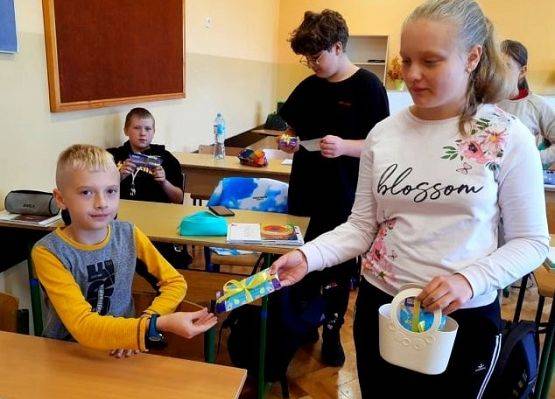 Uczennica daje koledze czekoladę z życzeniami
