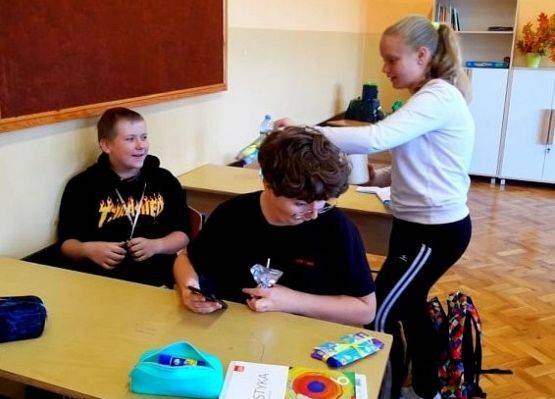 Uczennica daje koledze czekoladę z życzeniami