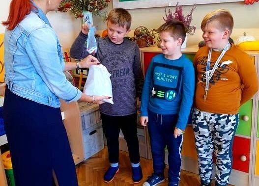 Nauczycielka rozdaje chłopcom upominki