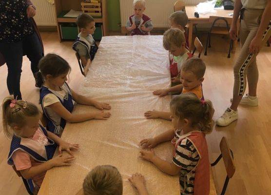 Dzieci klepią do rytmu rączkami po foli bąbelkowej