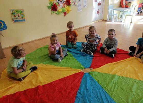 Dzieci słuchają opowiadania nauczyciela-zabawy z chustą