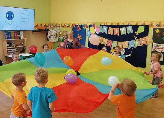 Dzieci bawią się balonami na chuście