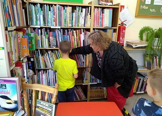 Pani bibliotekarka pomaga wybrać uczniowi książkę