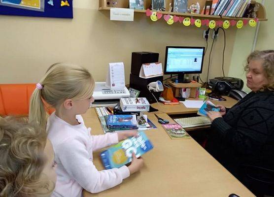 Uczennica wypożycza książkę