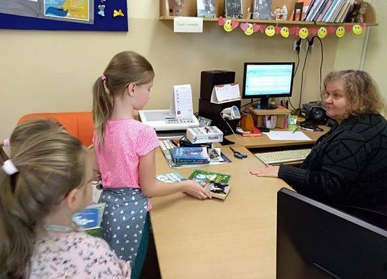 Uczennica wypożycza książkę