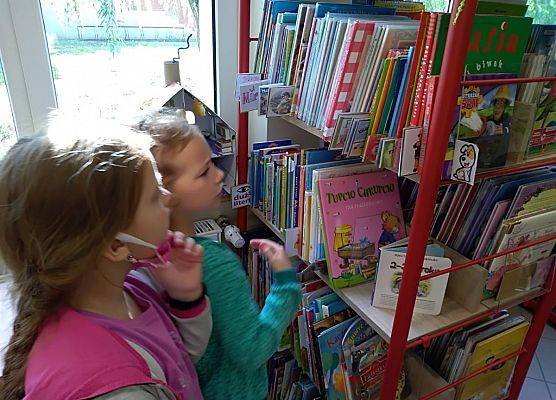 Uczennice szukają książek na półkach