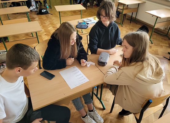 Uczniowie w grupie rozmawiają i sporządzają notatki