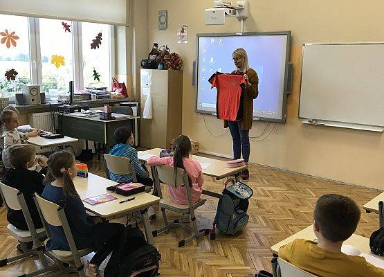Nauczycielka prezentuje uczniom koszulkę ratownika