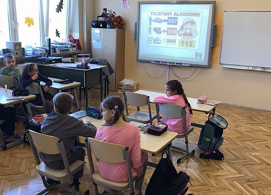 Dzieci czytają jakie informacje są zapisane na tablicy interaktywnej