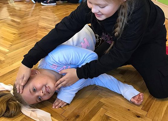 Dziewczynki dobrane w pary ćwiczą układanie w pozycję bezpieczną oraz udrożnianie dróg oddechowych.