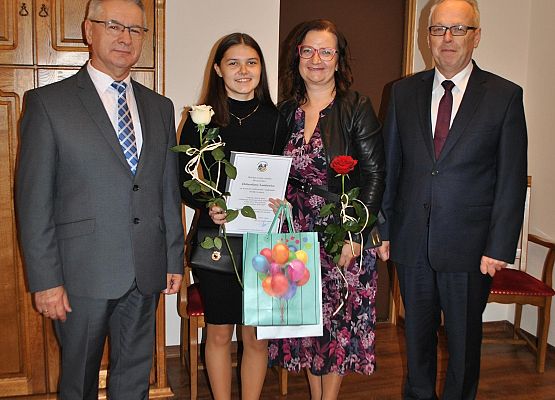 Pamiątkowe zdjęcie nagrodzonej uczennicy z wójtem, dyrektorem i rodzicem.