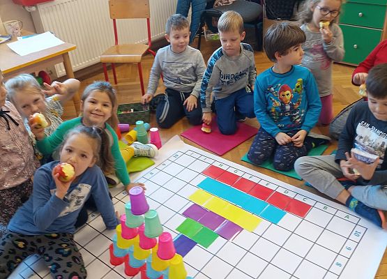 Dzieci odwzorowują wieżę z kubków na macie do kodowania za pomocą kolorowych kartoników