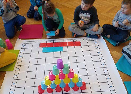 Dzieci odwzorowują wieżę z kubków na macie do kodowania