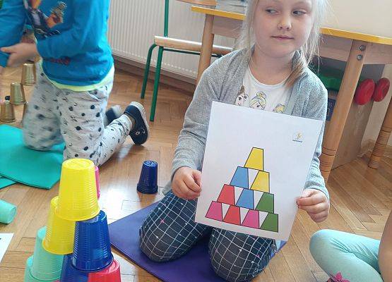 Dziewczynka ułożyła wieżę z kolorowych kubków według kodu