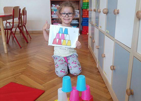 Dziewczynka ułożyła wieżę z kolorowych kubków według podanego wzoru