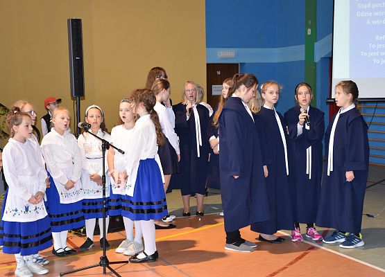 Uczennice ubrane w togi i stroje regionalne śpiewają