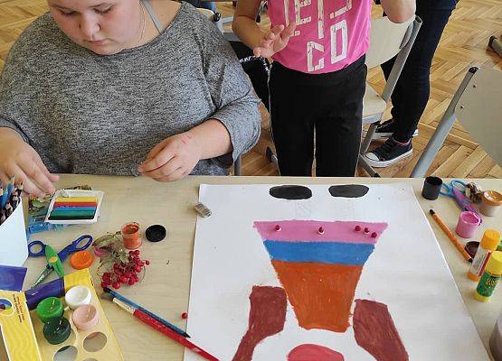 Dwie uczennica malują na arkuszu brystolu Borową Ciotkę