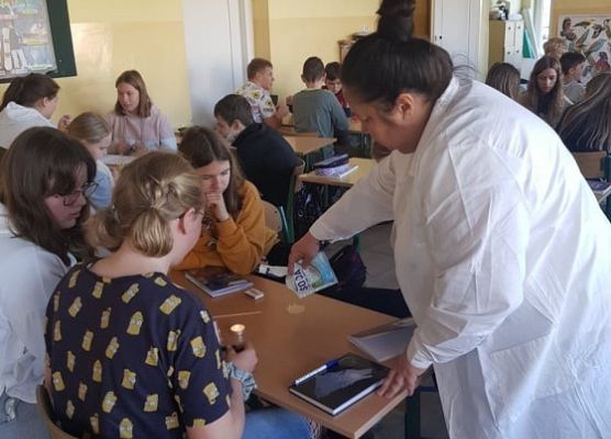 Nauczycielka wskazuje uczniom, jak poprawnie przeprowadzić doświadczenie
