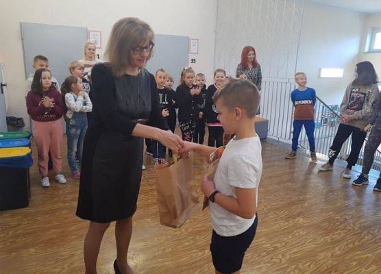 Uczeń odbiera dyplom i nagrodę od pani dyrektor.