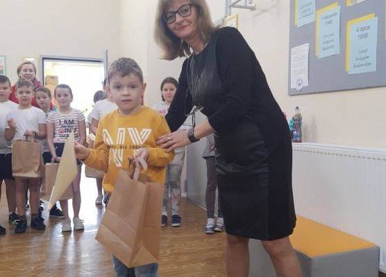 Uczeń odbiera dyplom i nagrodę od pani dyrektor.