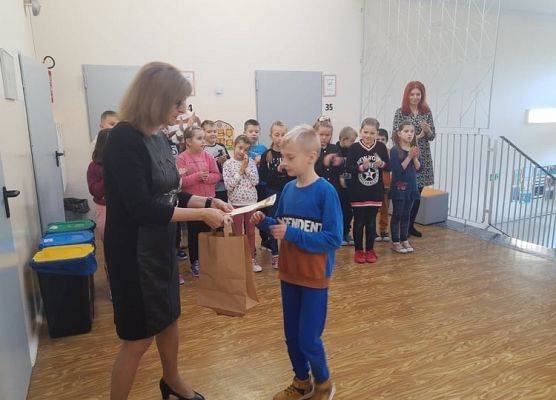 Uczeń odbiera dyplom i nagrodę od pani dyrektor.