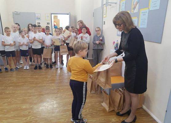 Uczeń odbiera dyplom i nagrodę od pani dyrektor.