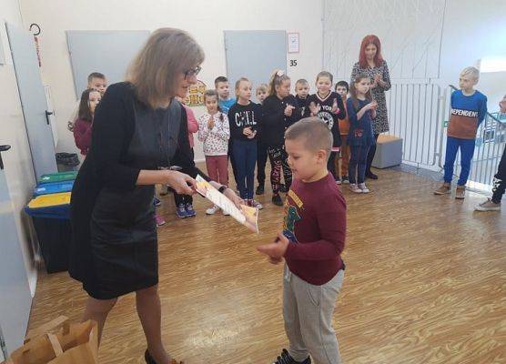 Uczeń odbiera dyplom i nagrodę od pani dyrektor.