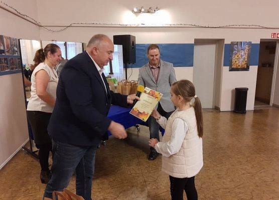 Uczennnica odbiera nagrodę od dyrektora GOKu.