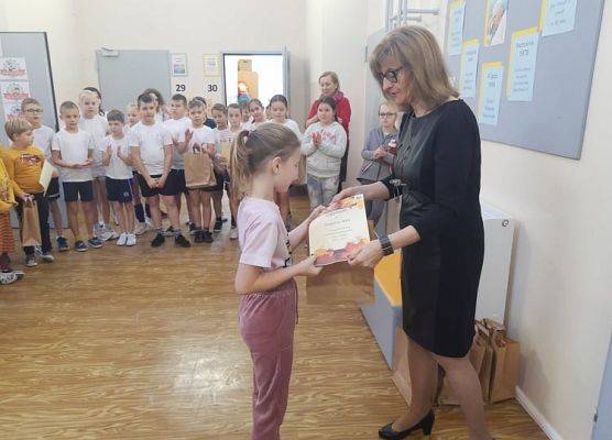 Uczennica odbiera dyplom i nagrodę od pani dyrektor.