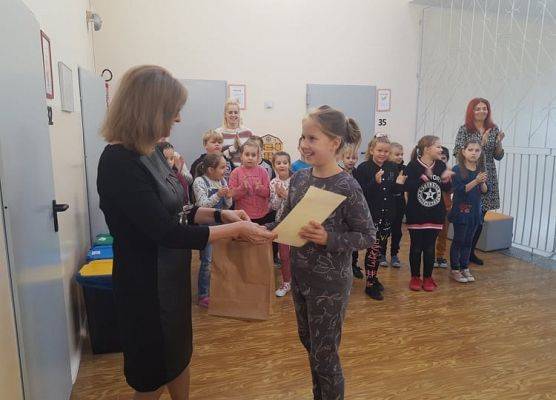 Uczennica odbiera dyplom i nagrodę od pani dyrektor.