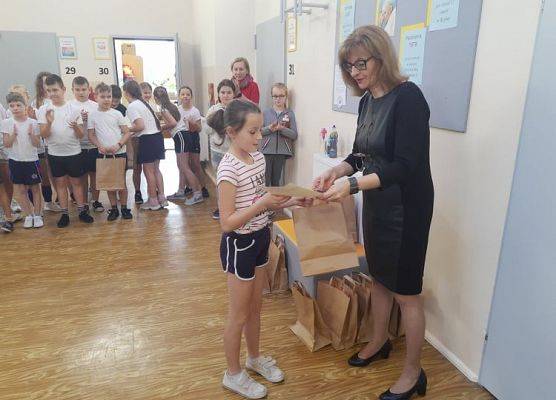 Uczennica odbiera dyplom i nagrodę od pani dyrektor.