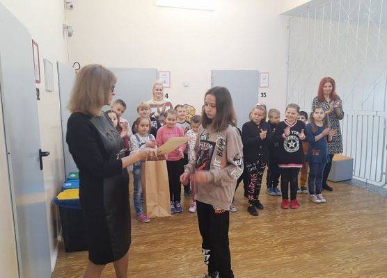 Uczennica odbiera dyplom i nagrodę od pani dyrektor.