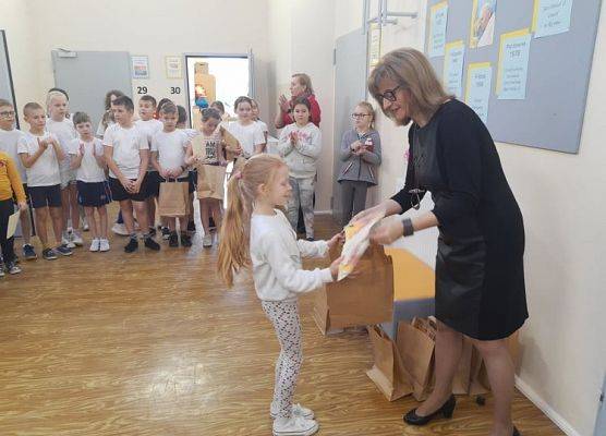 Uczennica odbiera dyplom i nagrodę od pani dyrektor