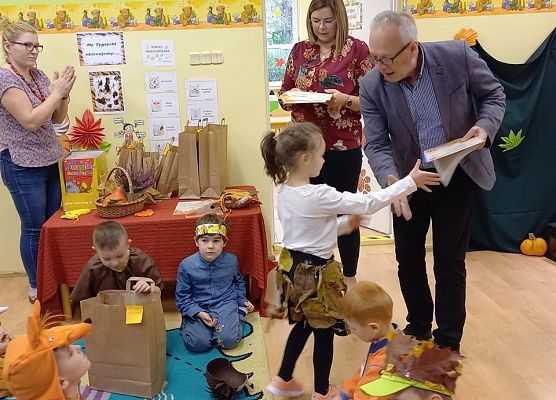 Dyrektor wręcza nagrodę dziewczynce za udział w jesiennym konkursie
