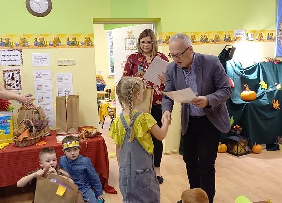 Dyrektor wręcza nagrodę dziewczynce za udział w jesiennym konkursie