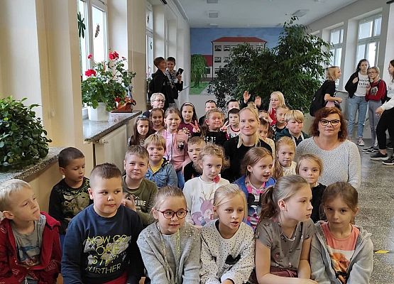 Uczniowie siedzą na ławkach i słuchają policjantów