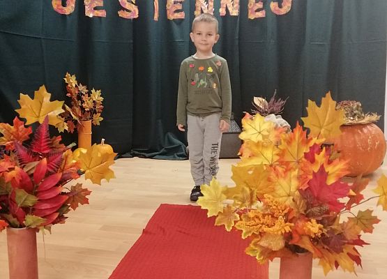 Chłopiec stoi na czerwonym dywanie