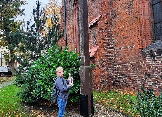 Uczeń stawia  znicz z napisem Szkoła Pamięta przy kościele Świętego Jakuba w Lęborku
