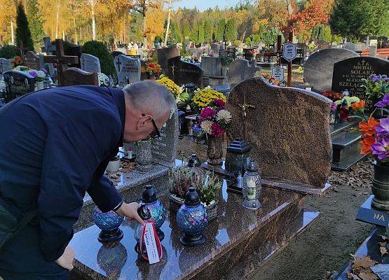 Dyrektor stawia na nagrobku znicz z napisem szkoła Pamięta